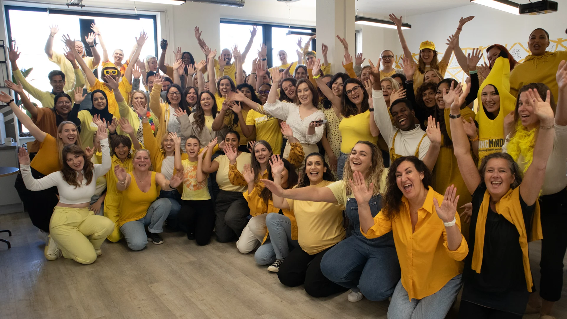 The YoungMinds team together, dressed in yellow with their hands in the air